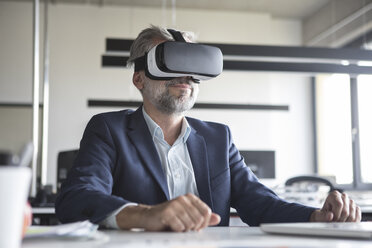 Businessman in office wearing virtual reality glasses - RBF05308