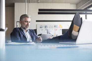 Relaxed businessman at office desk - RBF05310