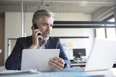 Geschäftsmann bei der Arbeit am Bürotisch - RBF05311