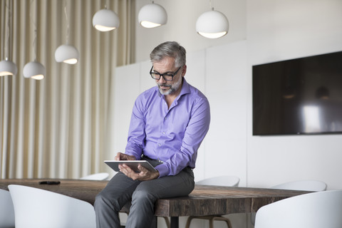 Geschäftsmann im Sitzungssaal mit Tablet, lizenzfreies Stockfoto