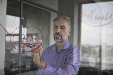 Businessman in office writing on glass wall - RBF05331