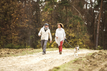 Älteres Paar geht mit ihrem Hund im Wald spazieren - HAPF01152