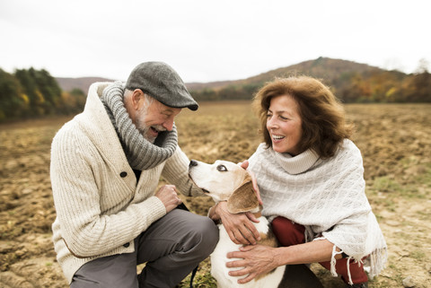 Happy senior couple with dog in nature stock photo