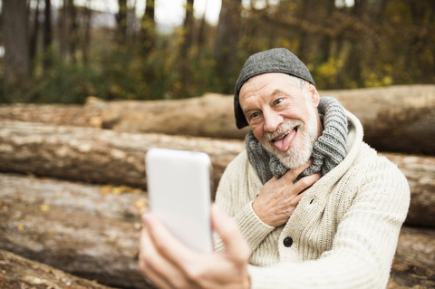Portrait of senior man pulling funny faces while taking selfie stock photo
