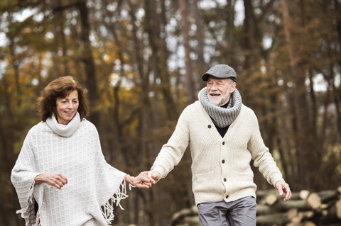 Älteres Paar geht Hand in Hand im Wald spazieren, lizenzfreies Stockfoto