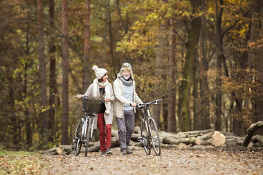 Seniorenpaar mit Fahrrädern im herbstlichen Wald - HAPF01166