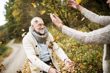 Glücklicher älterer Mann und seine Frau spielen mit Herbstblättern - HAPF01176