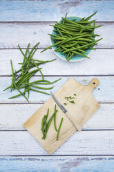 Bowl of green beans, wooden board and kitchen knife on wood - LVF05645