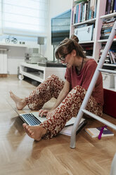 Frau zu Hause auf dem Boden sitzend mit Laptop - MGOF02682