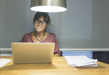 Smiling woman using laptop at desk - MGOF02685