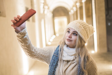 Porträt einer jungen Frau mit Wolfsmütze, die ein Selfie mit ihrem Handy macht - SIPF01149