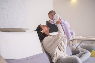 Mother holding up baby girl at home - SIPF01151