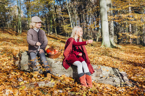 Hänsel und Gretel, Junge und Mädchen sitzen im Wald auf einem Baumstamm, lizenzfreies Stockfoto