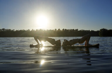 Zwei Frauen machen Yoga auf dem Paddleboard bei Sonnenuntergang - FMKF03271