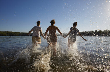 Back view of friends running in a lake - FMKF03279