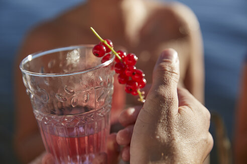 Die Hand hält ein Getränk mit roten Johannisbeeren - FMKF03284