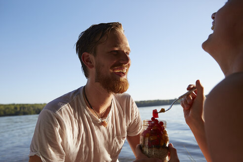 Glückliches Paar an einem See bei einem gesunden Snack - FMKF03285
