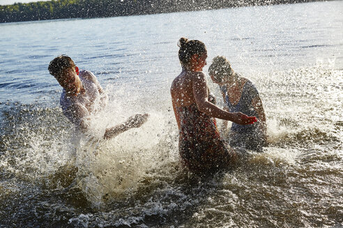 Verspielte Freunde beim Planschen in einem See - FMKF03286