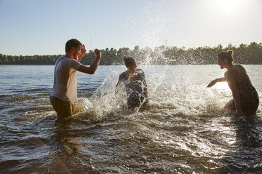 Verspielte Freunde beim Planschen in einem See - FMKF03287