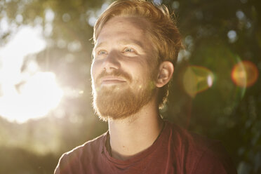 Smiling young man in backlight outdoors - FMKF03296