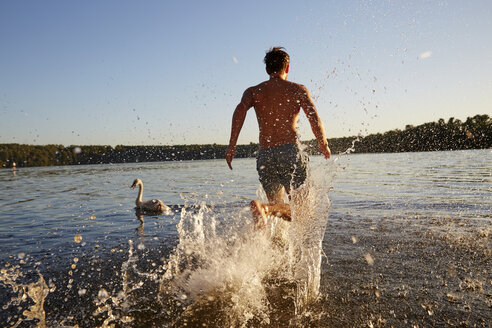 Rückenansicht eines Mannes, der in einem See läuft - FMKF03298