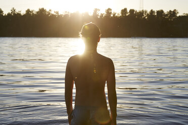 Rückenansicht eines Mannes in einem See bei Sonnenuntergang - FMKF03300