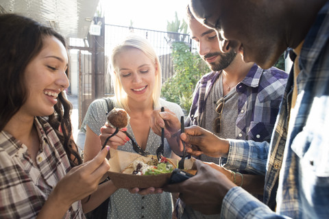 Happy friends sharing takeaway food outdoors stock photo