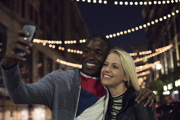 Glücklicher junger Mann mit Freundin, der ein Selfie bei Nacht macht - WEST22156