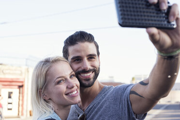 Glücklicher junger Mann mit Freundin, der ein Selfie macht - WEST22160