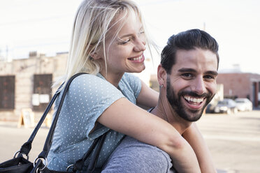 Happy young man carrying girlfriend piggyback - WEST22161