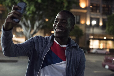 Lächelnder junger Mann macht ein Selfie bei Nacht - WEST22196