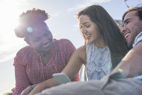 Glückliche Freunde im Freien mit Mobiltelefon - WESTF22242