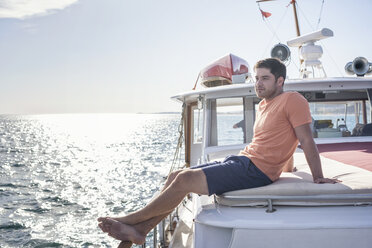 Junger Mann sitzt auf einem Boot - WESTF22259