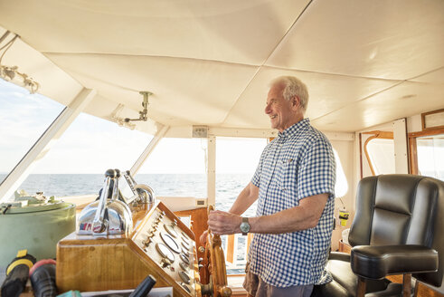 Confident senior man steering a boat - WESTF22290
