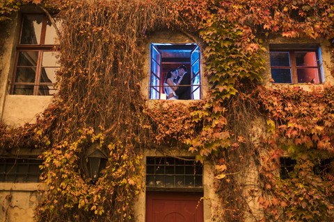 Brautpaar beim Kuss hinter dem Fenster, lizenzfreies Stockfoto