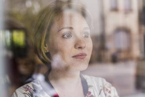 Junge Frau schaut aus dem Fenster - UUF09429