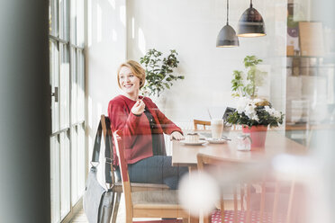 Lächelnde junge Frau in einem Kaffeehaus - UUF09433