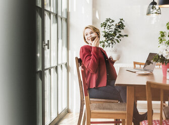 Smiling young woman using cell phone in a cafe - UUF09434