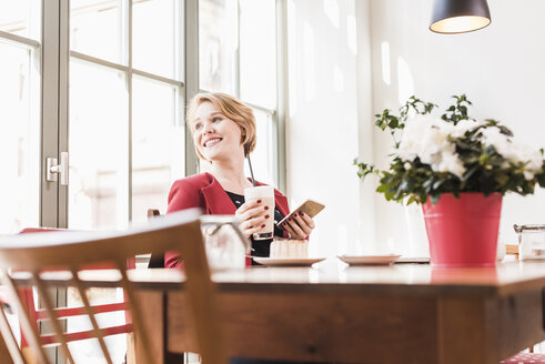 Lächelnde junge Frau in einem Kaffeehaus - UUF09437