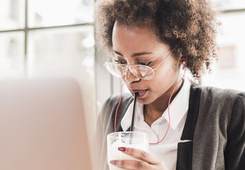 Junge Frau mit Laptop trinkt Latte Macchiato - UUF09453