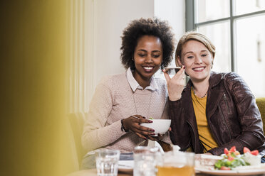 Zwei junge Frauen telefonieren in einem Cafe - UUF09463