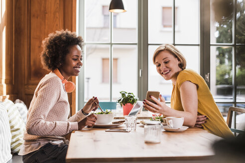 Zwei junge Frauen mit Handy treffen sich in einem Cafe - UUF09472