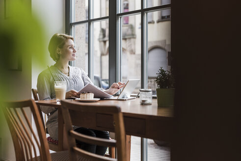 Junge Frau mit Tablet in einem Café und Blick aus dem Fenster - UUF09479