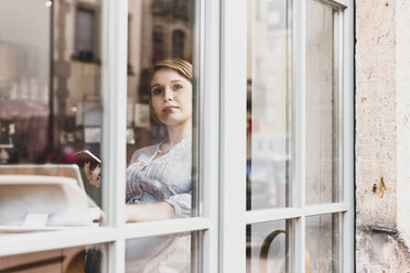 Young woman with tablet and cell phone in a cafe looking out of window - UUF09481