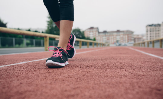 Woman walking on tartan track - DAPF00496