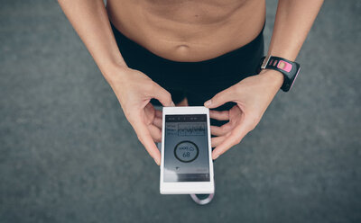 Sportler schaut auf sein Smartphone mit Trainingsdaten auf dem Display - DAPF00499