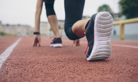 Woman on tartan track in starting position stock photo