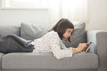 Girl lying on the couch using mini tablet - LVF05675