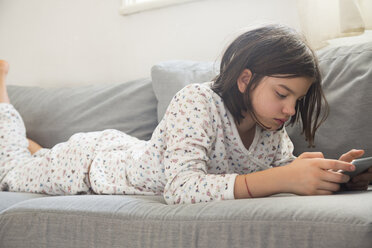 Girl lying on the couch using mini tablet - LVF05676