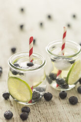 Glasses of infused water with lime, blueberries and ice cubes - JUNF00709